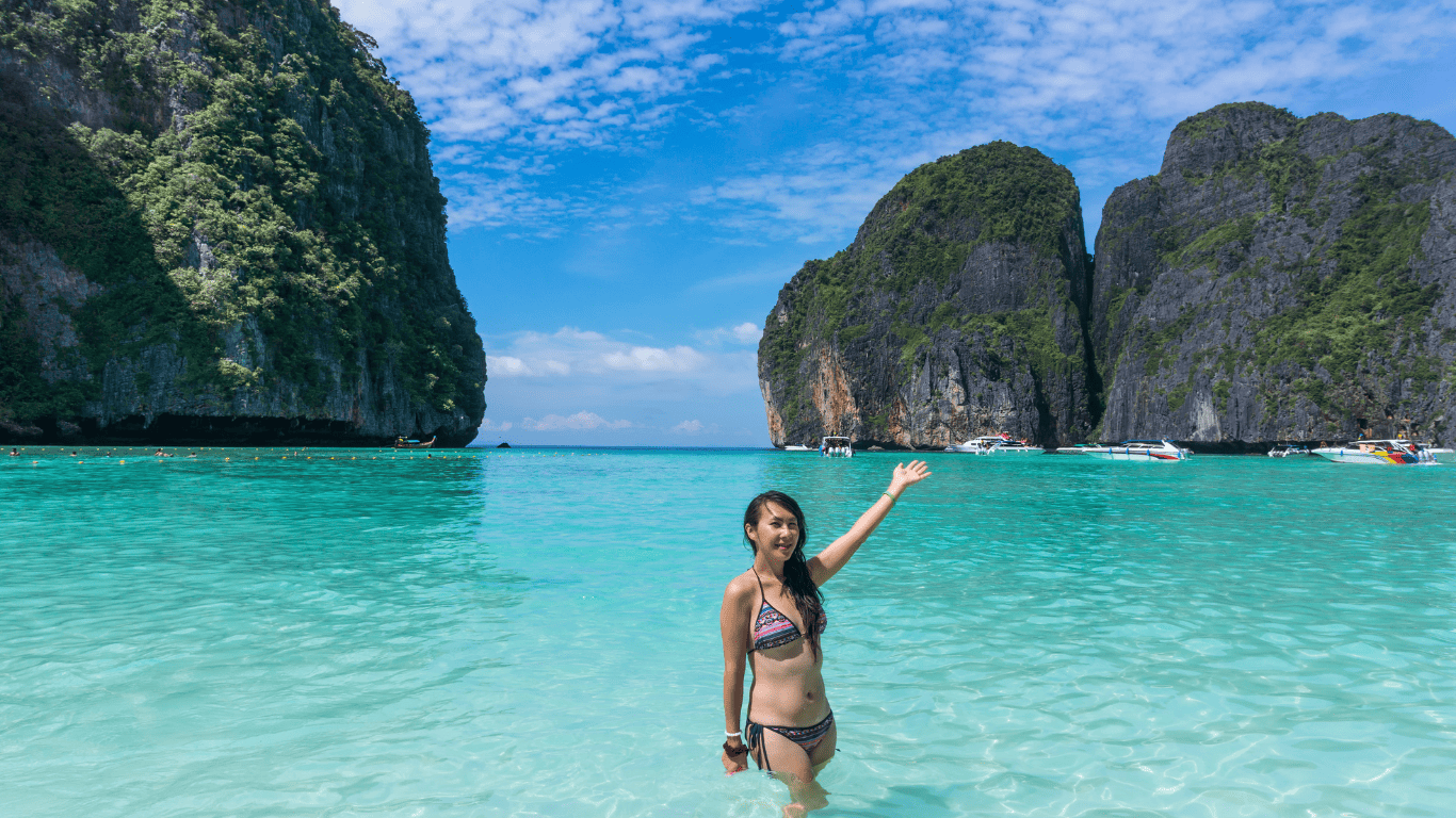 Girl in bikini standing in maya bay with her hands up