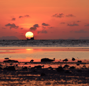 Phuket sunrise golden rocky beach reflection.